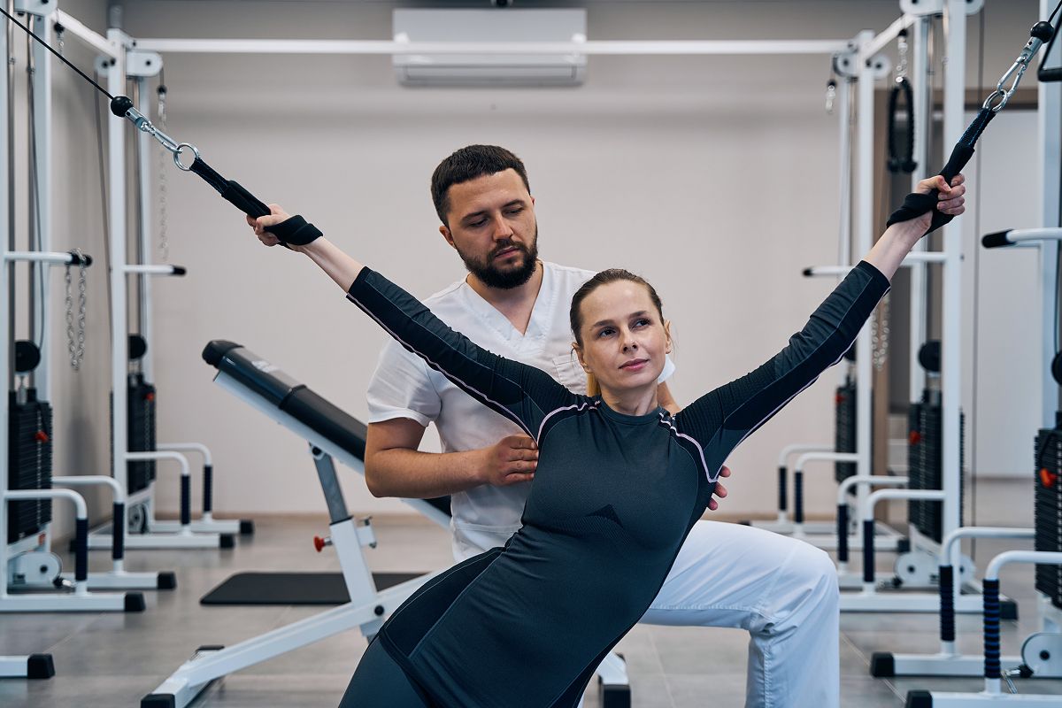 Frau trainiert mit Unterstützung eines Trainers zur Muskelstärkung