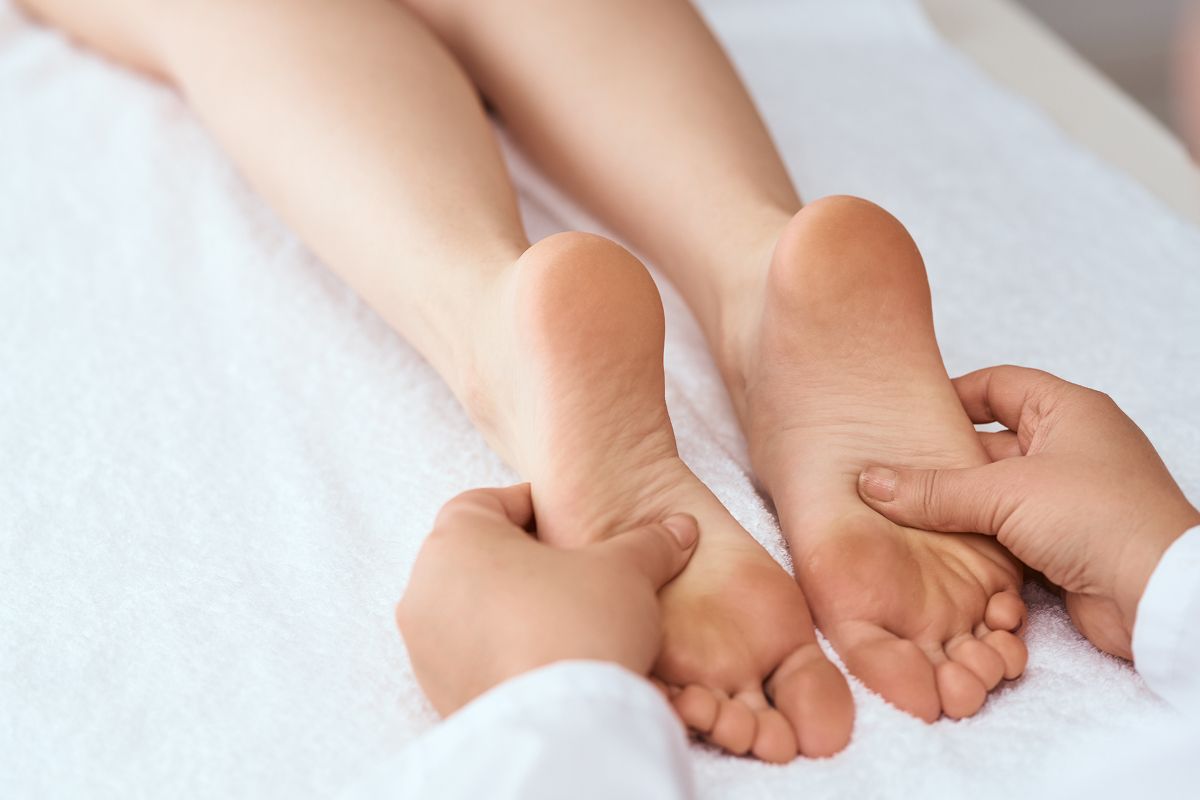 Eine entspannende Fußmassage auf einer weißen Liege.